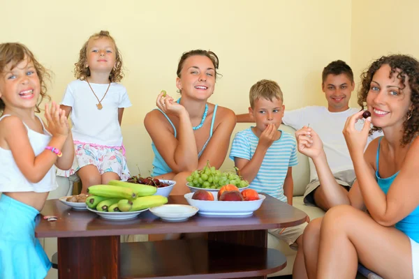 Gyermekes, nagy, boldog család eszik gyümölcsöt hangulatos szobában — Stock Fotó
