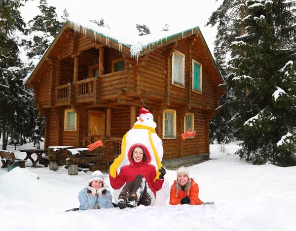 Три девушки со снеговиком и коллажем зимнего дома — стоковое фото