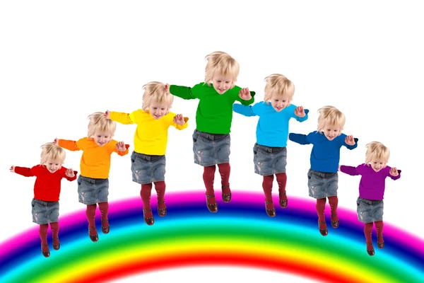 Children with rainbow color dress are jumping on the rainbow, co — Stock Photo, Image