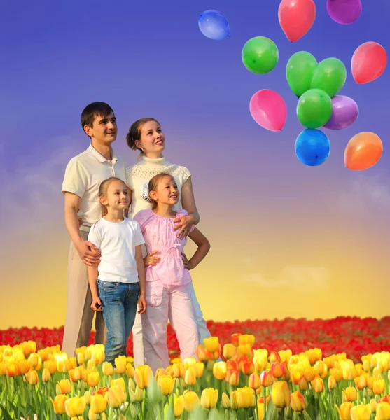 Familia de cuatro en campo de tulipanes y collage de globos — Foto de Stock