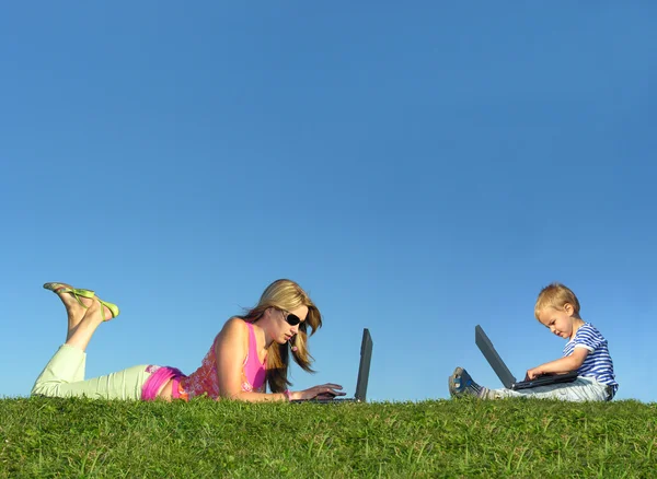 Mor med barn med bärbara datorer på gräs kollage — Stockfoto