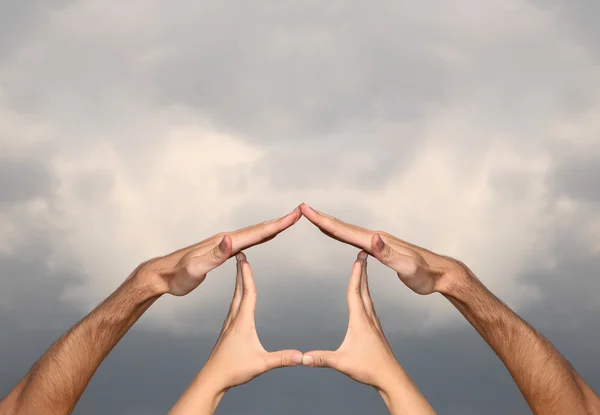 Symbol home made from hands on cloudy sky — Stock Photo, Image