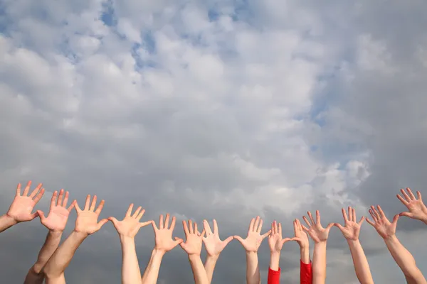 Raised hands on cloudy sky background — Stock Photo, Image