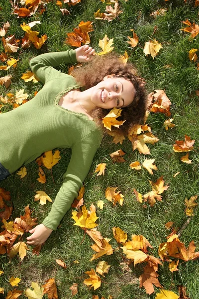 Woman with the yellow leaf lies on the grass — Stock Photo, Image