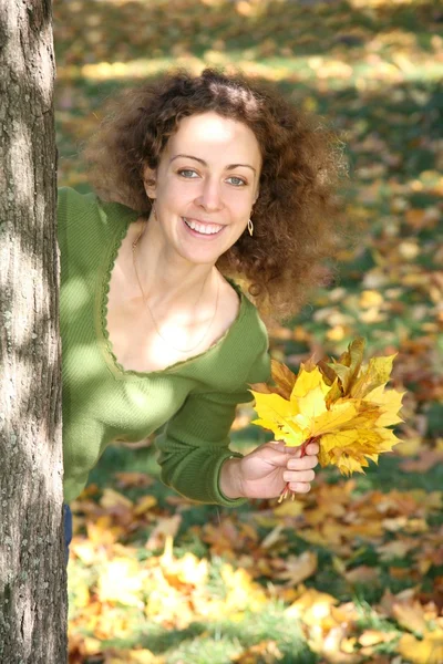 Wygląda kobieta z żółty liść z drzewa — Zdjęcie stockowe