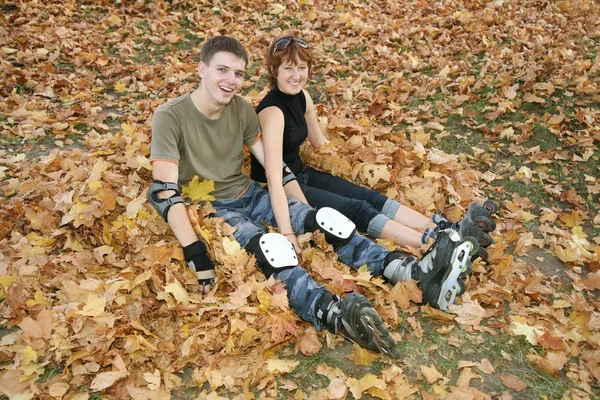 Giovane coppia rullo sedersi su foglie gialle — Foto Stock