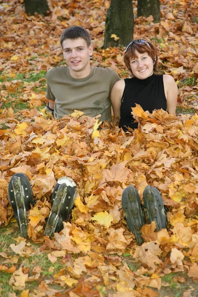 Junges Rollerpaar sitzt in gelben Blättern — Stockfoto