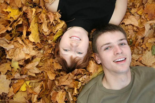 Young couple lies on yellow leaves — Stock Photo, Image