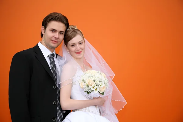 Verloofde met de bruid tegen de oranje achtergrond — Stockfoto