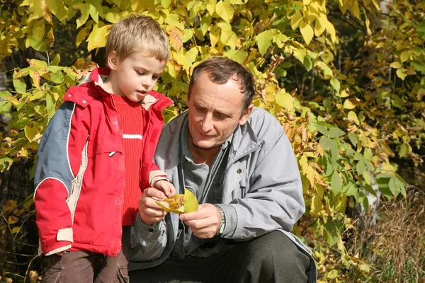 Grandfather with the grandson in the park in autumn — Stock Photo, Image