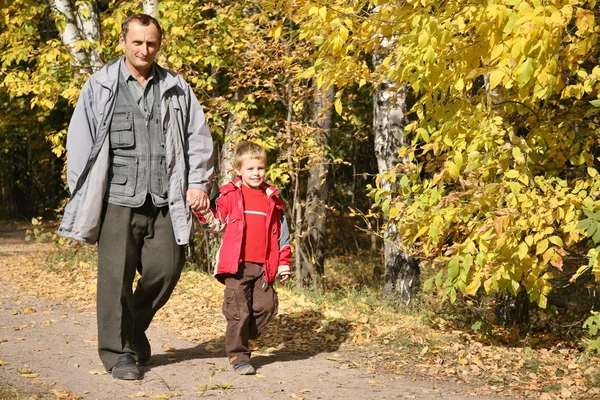 Farfar med barnbarn promenad i park i höst — Stockfoto
