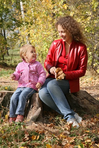 Mãe com a filha senta-se no parque no outono — Fotografia de Stock