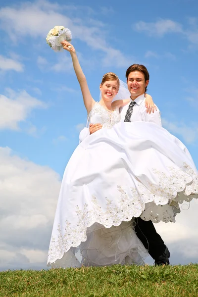 Verloofde houdt bruid op de handen op naar de weide — Stockfoto