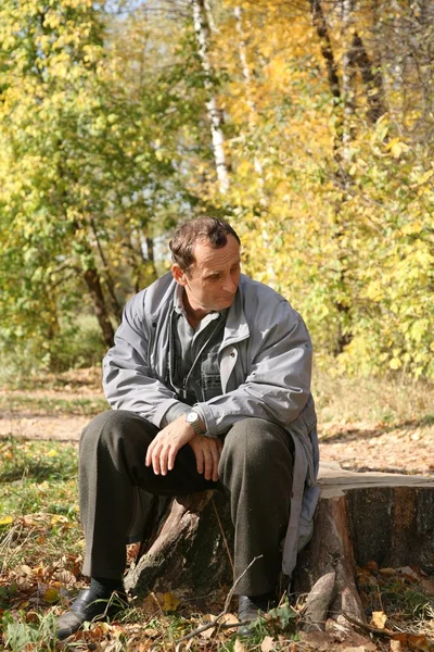 Oudere man zit in het park in het najaar van — Stockfoto