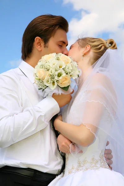 Жених, невеста, поцелуй, букет и небо — стоковое фото