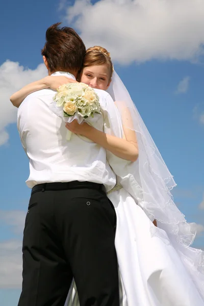 Sposa abbraccia fidanzato sullo sfondo del cielo — Foto Stock