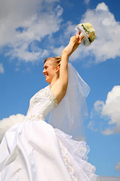 Sposa tiene il bouquet in testa sullo sfondo del cielo — Foto Stock