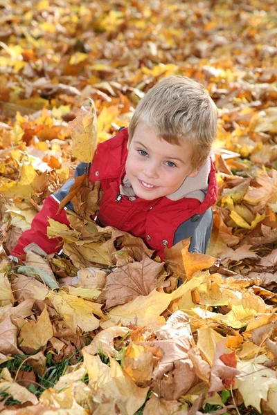 Enfant parmi les feuilles tombées — Photo