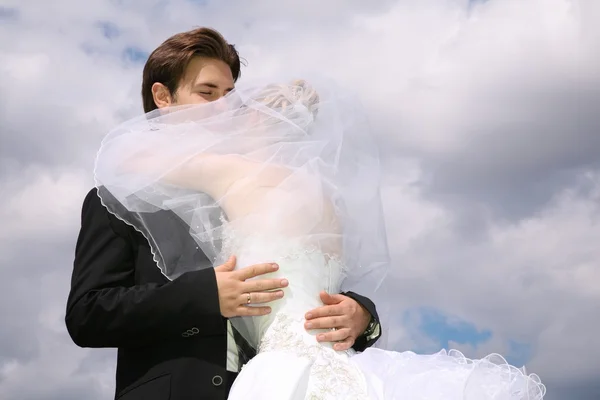 Noivo e noiva se beijam no fundo das nuvens — Fotografia de Stock