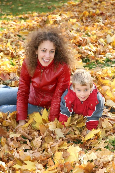 Matka a dítě sedět mezi spadané listí — Stock fotografie