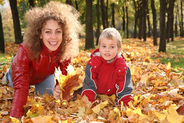 Akçaağaç yaprakları üzerinde çocuk ile anne — Stok fotoğraf