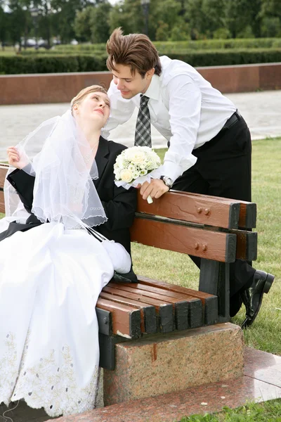 Nevěsta sedí na lavičce a dívá se na její snoubenec — Stock fotografie