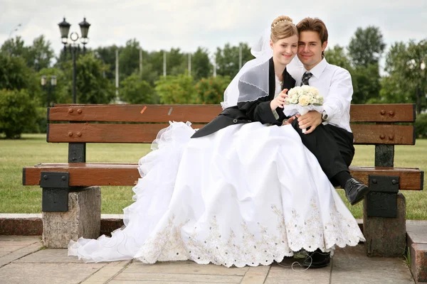 Невеста с женихом они сидят на скамейке — стоковое фото