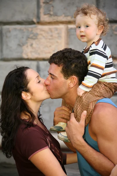 Homem com a criança beija a mulher — Fotografia de Stock