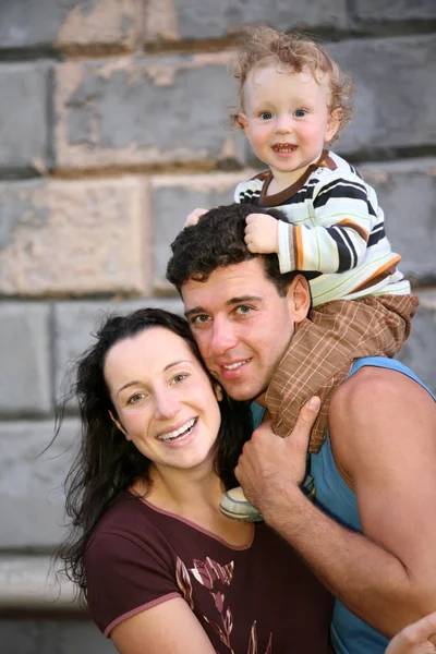 Улыбаясь жена и муж с ребенком на плечах — стоковое фото