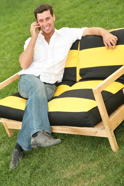 Człowiek z telefonu, który siedzi na ławce — Zdjęcie stockowe