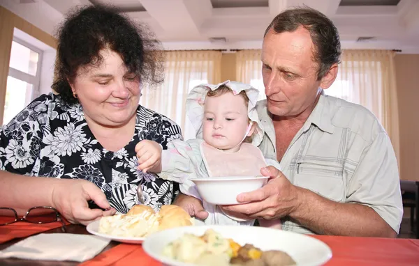 Бабушка с дедушкой кормят ребенка — стоковое фото