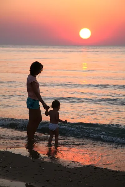 Matka z dzieckiem na zachód słońca na morzu — Zdjęcie stockowe