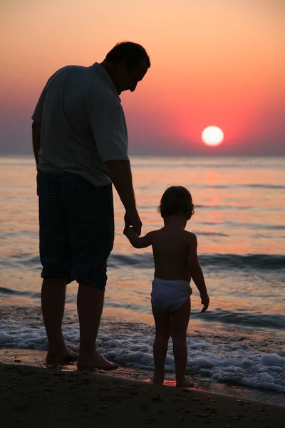 Grand-père avec petite-fille au coucher du soleil en mer — Photo