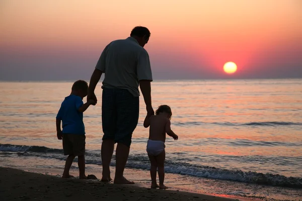 Grandfather with children on sunset at sea — Stock Photo, Image