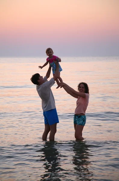 Папа с мамой и ребенком в море на закате — стоковое фото