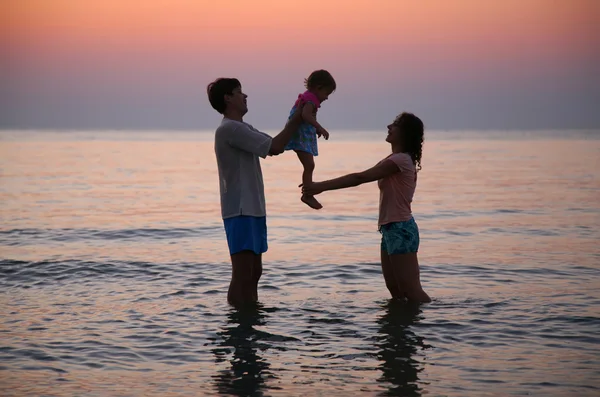 Мама с папой и ребенком в море на закате — стоковое фото