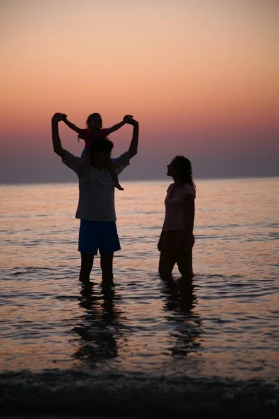 Rodina v moři alongshore na západ slunce — Stock fotografie