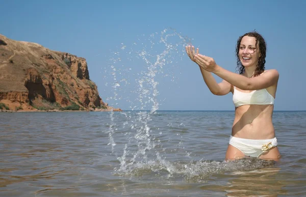 Mladá žena v moři sype do vody — Stock fotografie