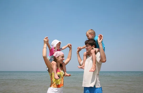 Genitori tengono i bambini sulla riva del mare — Foto Stock