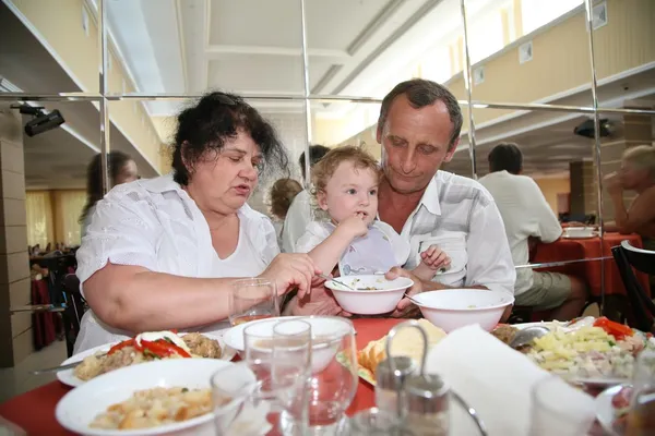 Бабуся з дідом годує дитину в їдальні — стокове фото