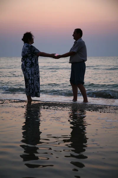 Дідусь з бабусею на заході сонця в морі — стокове фото