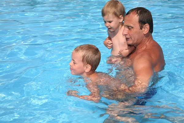 Дедушка с внуками в бассейне — стоковое фото