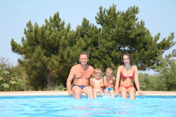 Donna e uomo con bambini al bordo piscina — Foto Stock