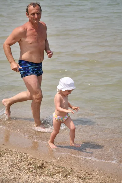 Dziadek z wnuczka biegać do plaży — Zdjęcie stockowe