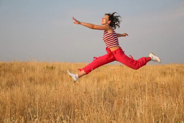 Mladá žena skok na louce — Stock fotografie