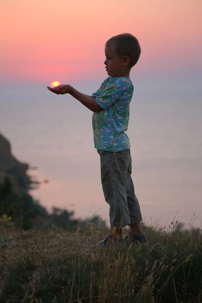 Pojken håller solen i händerna — Stockfoto