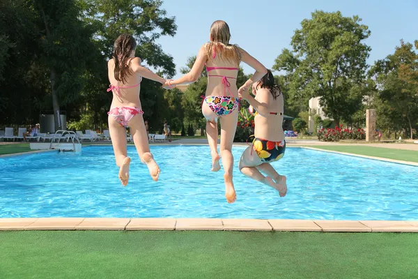 Three girls jump in pool — Stock Photo, Image
