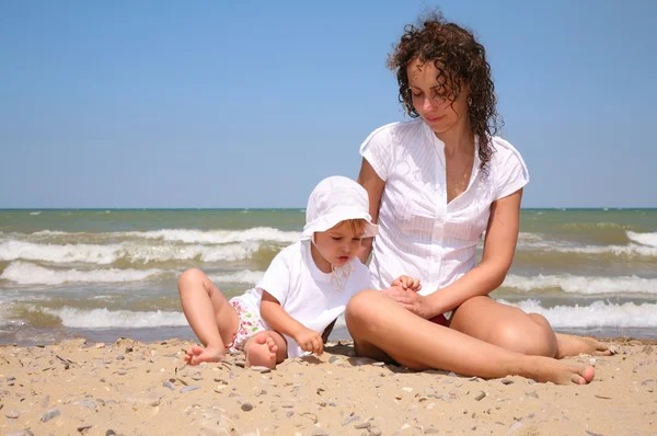 Мама з дитиною сидить на піску в морі . — стокове фото