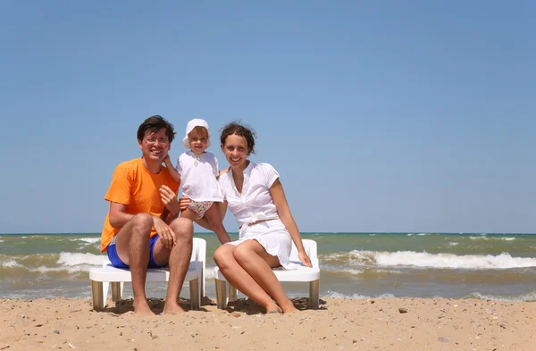 Mum, the daddy and the child sit on chairs near the sea. — Stock Photo, Image