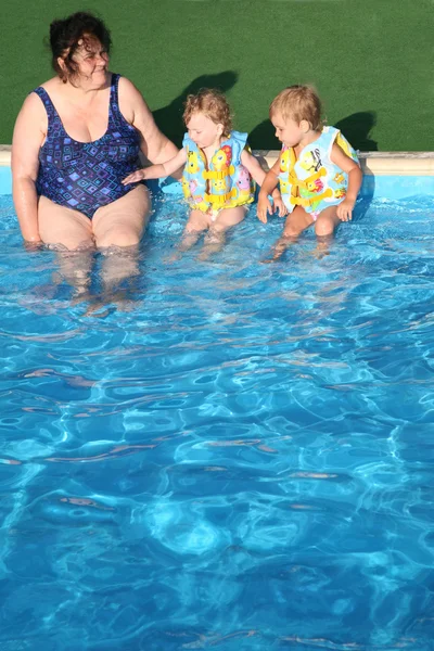 Η γιαγιά και τα παιδιά κάθονται στην πισίνα. — Φωτογραφία Αρχείου